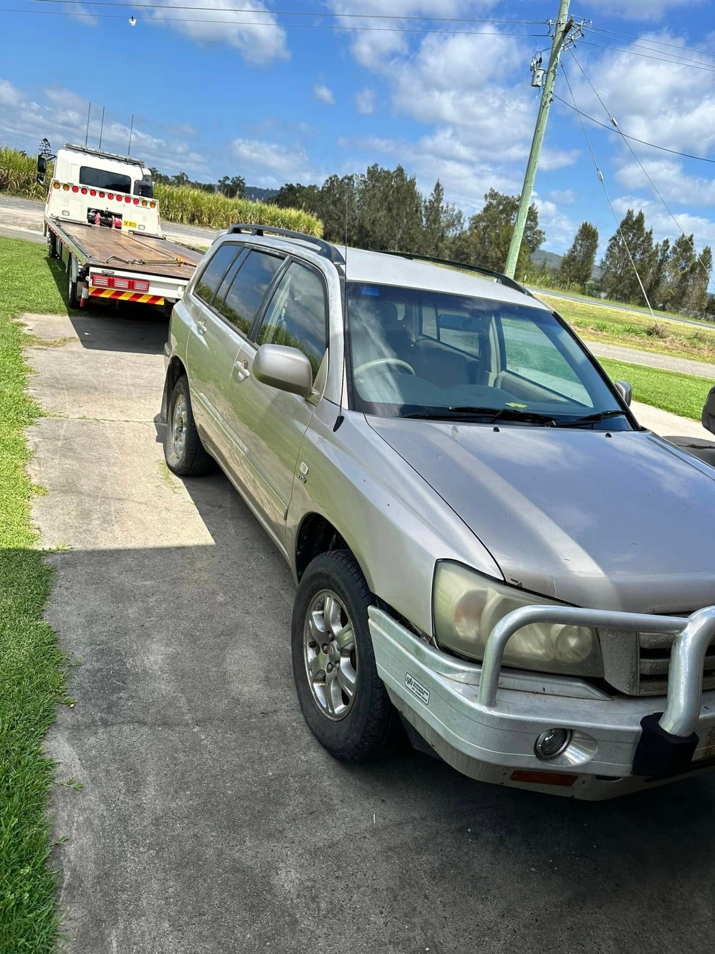 Gold four-wheel drive on a rural Maclean driveway with a Clarence Valley Tow Trucks tilt tray attending a roadside callout