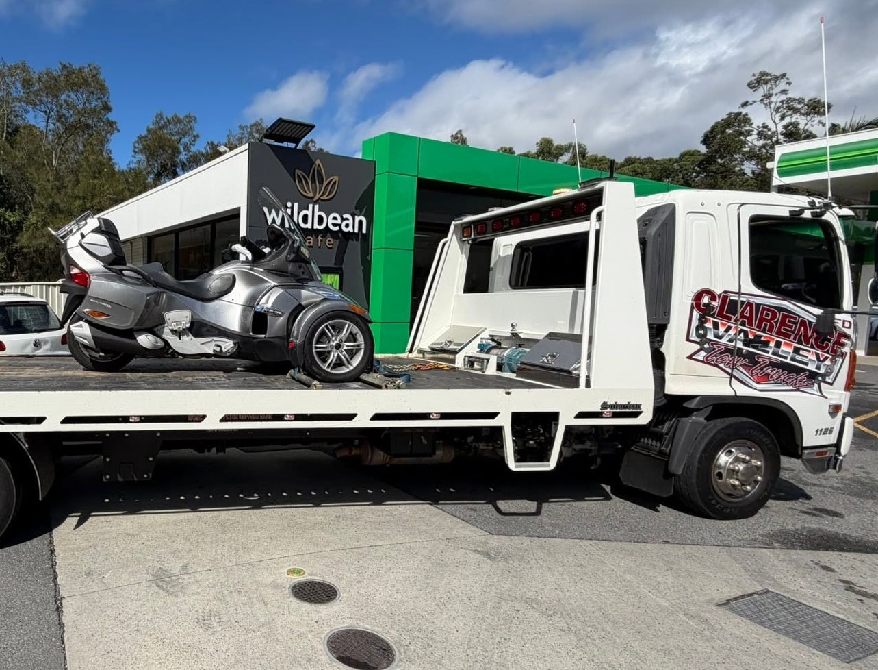 Motorcycle secured upright on a Clarence Valley Tow Trucks tilt tray at a service station