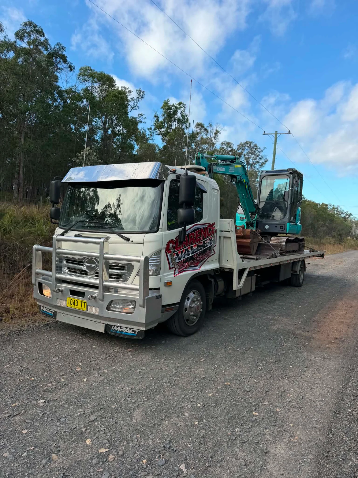 Mini excavator loaded on the tilt tray on a dirt road