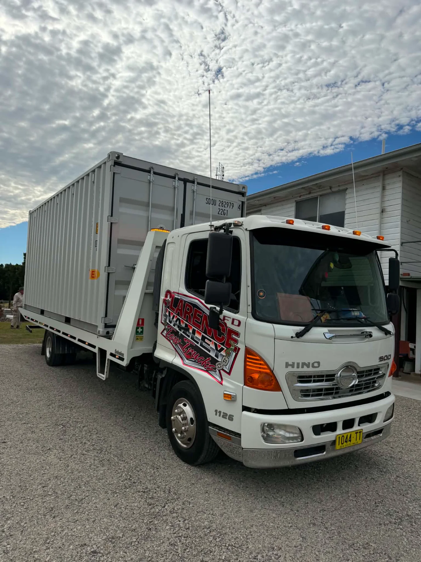A twenty foot shipping container on the truck tray beside a house