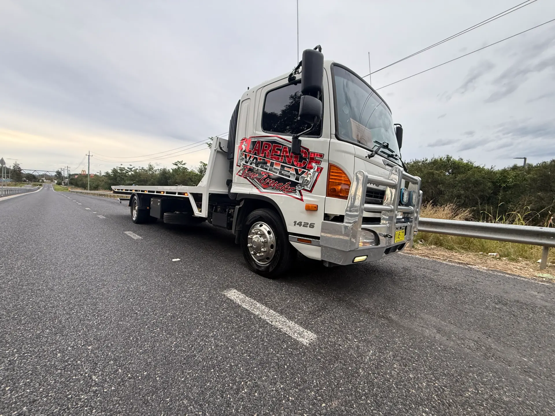 Clarence Valley Tow Trucks tilt tray truck stopped on a highway shoulder at dusk