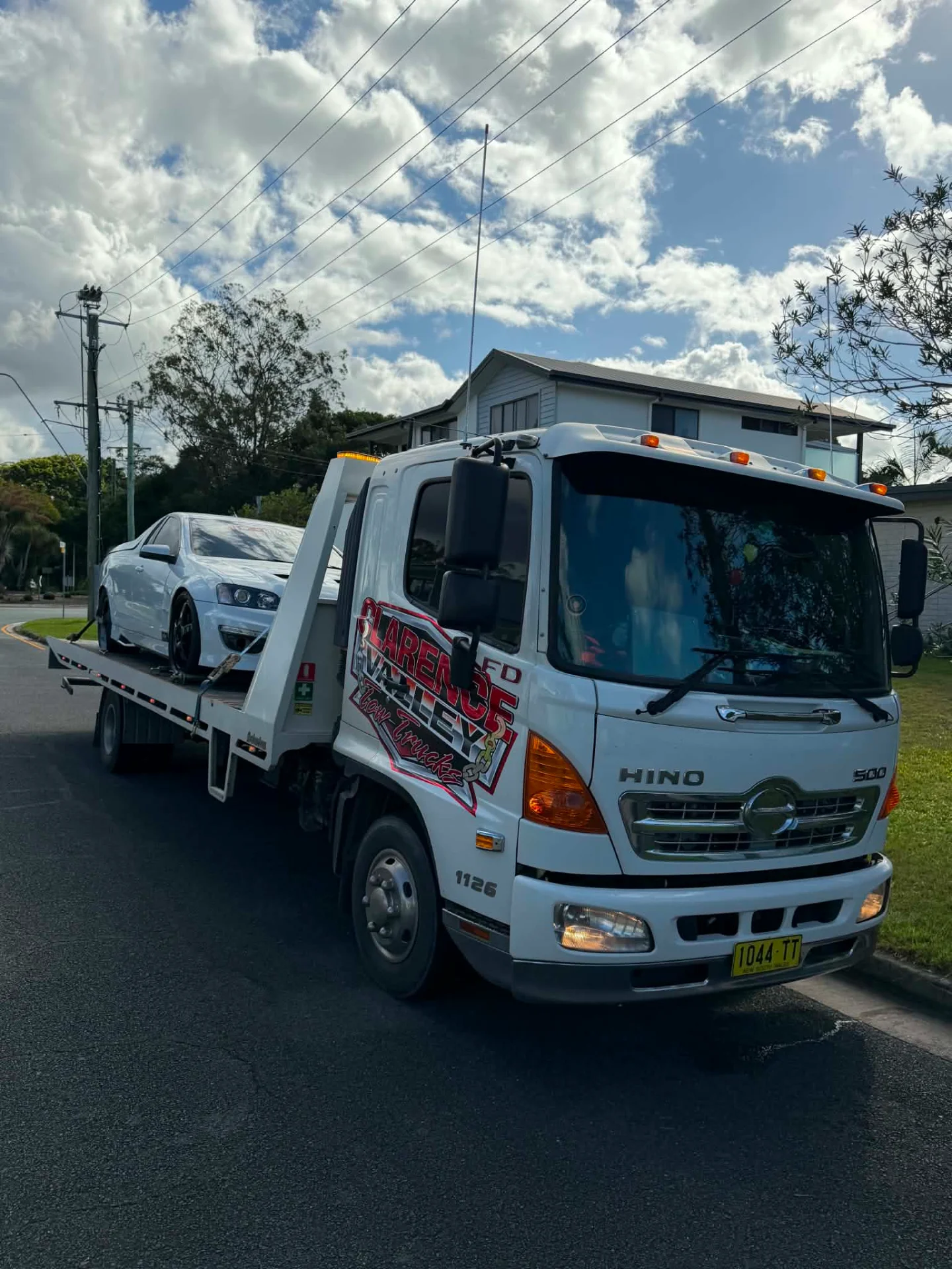 White sedan being loaded on the tray on a quiet residential street