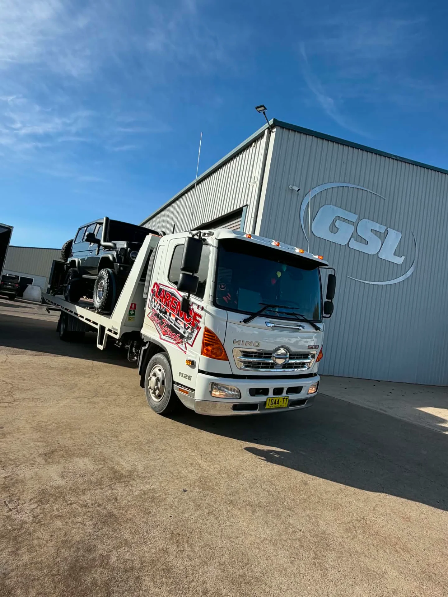 A four-wheel drive on the tilt tray outside a steel warehouse