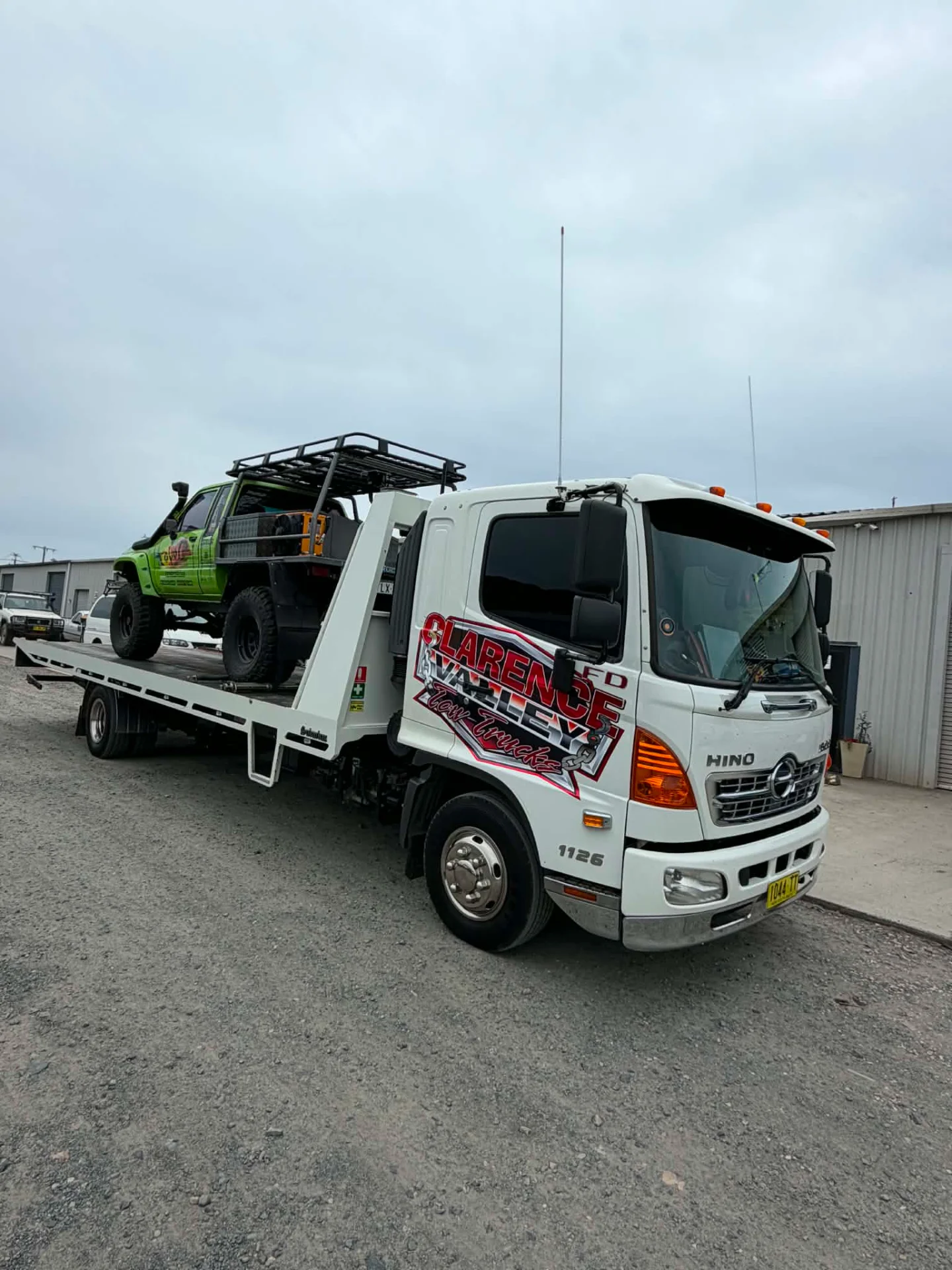 A green modified four-wheel drive on the tray outside a shed