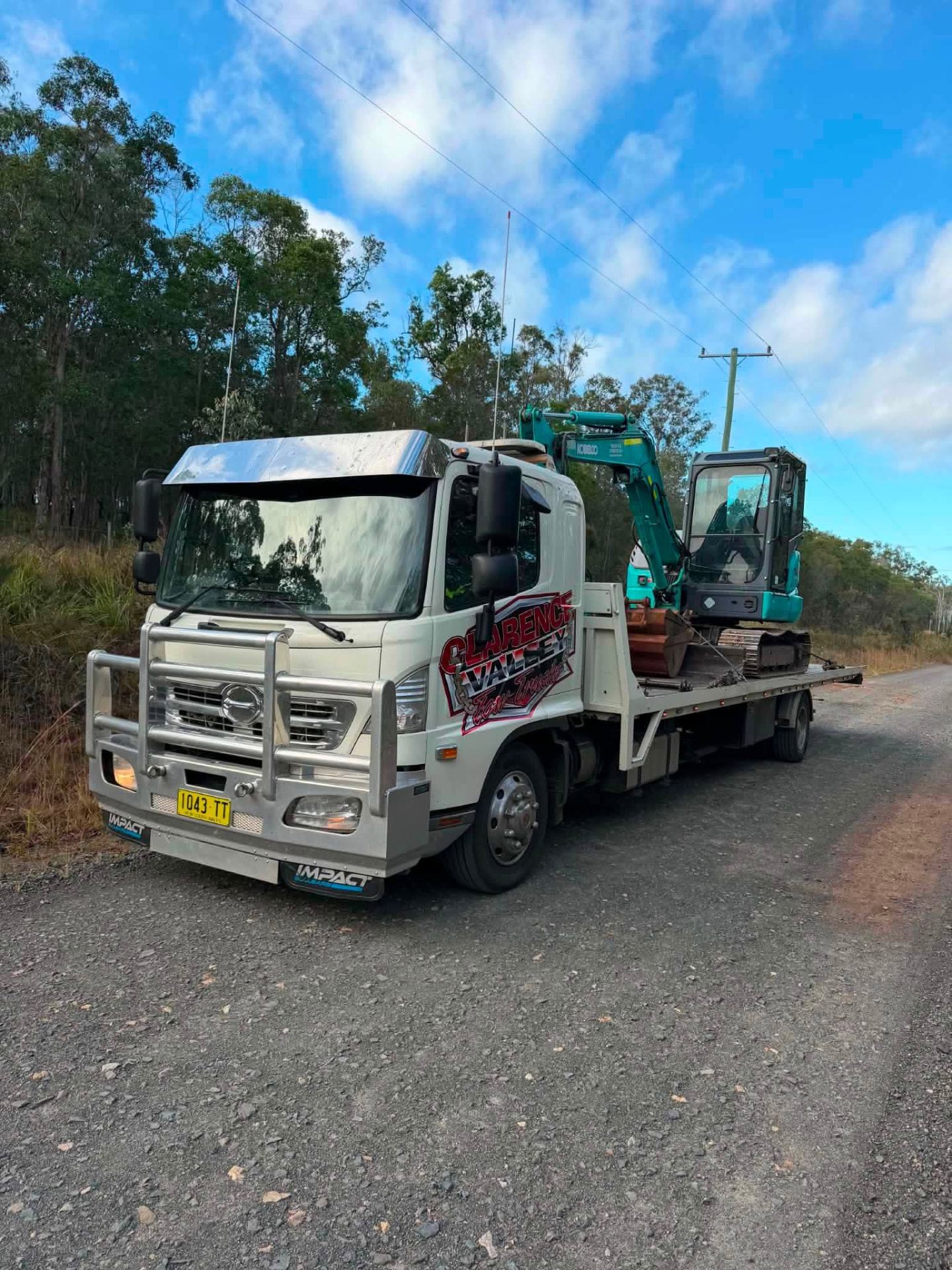 Excavator loaded on a Clarence Valley Tow Trucks machinery float on a gravel road